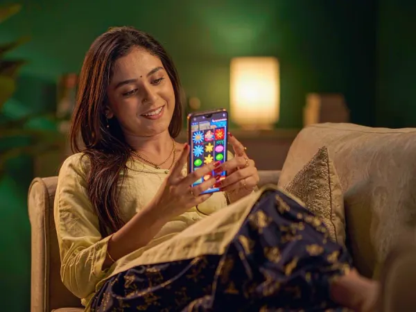 sportsbet.io + Woman smiling at a colourful slot game on her phone