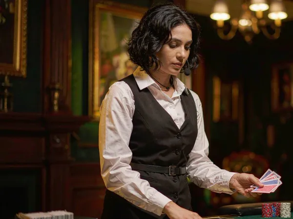 sportsbet.io + Woman dealer dealing cards onto a green table with chip stacks