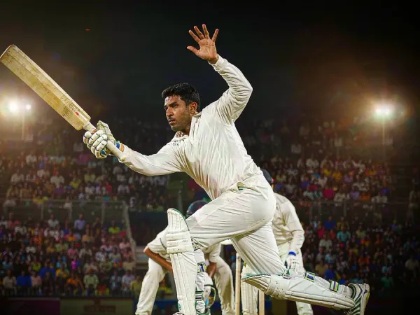 sportsbet.io + Cricketer in white kit playing a shot under floodlights in a packed stadium