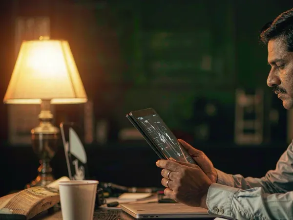 sportsbet.io + Man viewing match data on a tablet beside a cricket bat and coffee