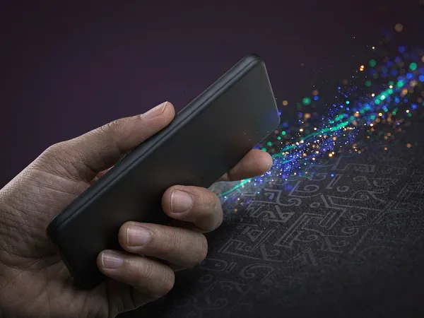 sportsbet.io + Hand holding a smartphone with colourful light particles
